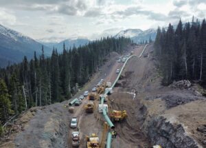 Crews and machinery working in rugged terrain to construct and secure pipelines.