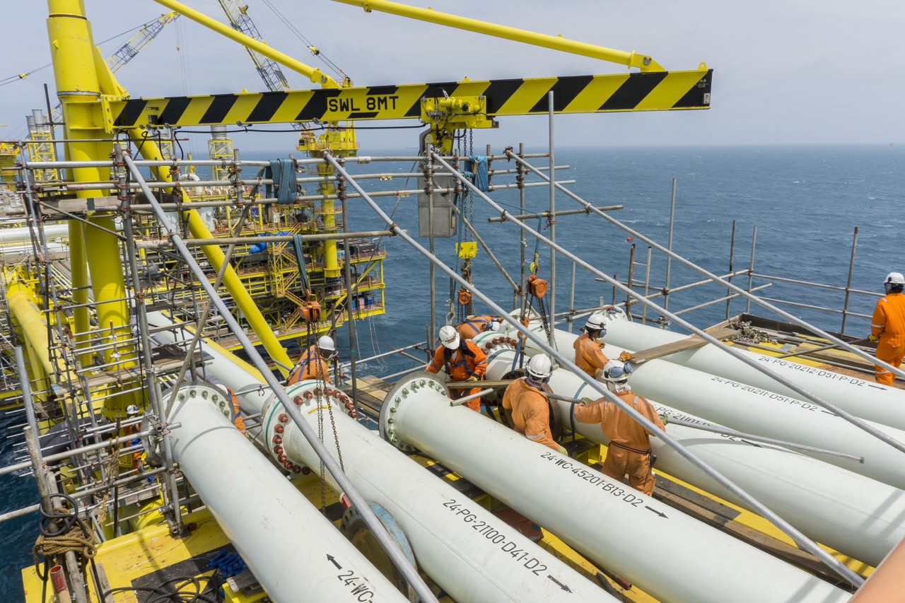 Offshore pipeline workers perform bolting tasks on large pipes, ensuring secure and efficient operations at sea.