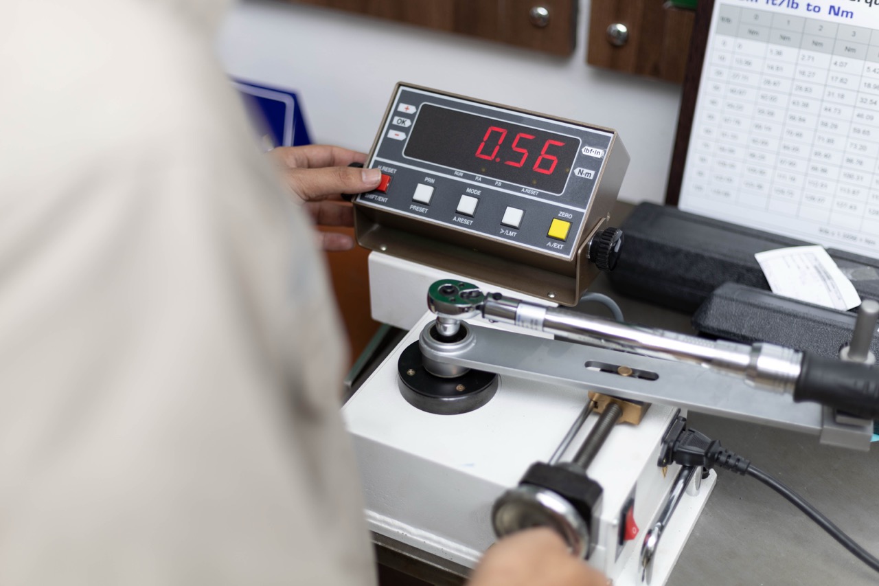 Torque wrench calibration service technician uses digital torque tester to calibrate manual torque wrench.
