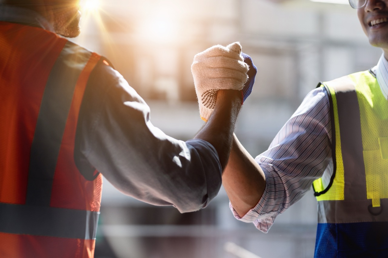 Safety-clad workers shake hands, showing how lab ISO 17025 accreditation reduces project risks.