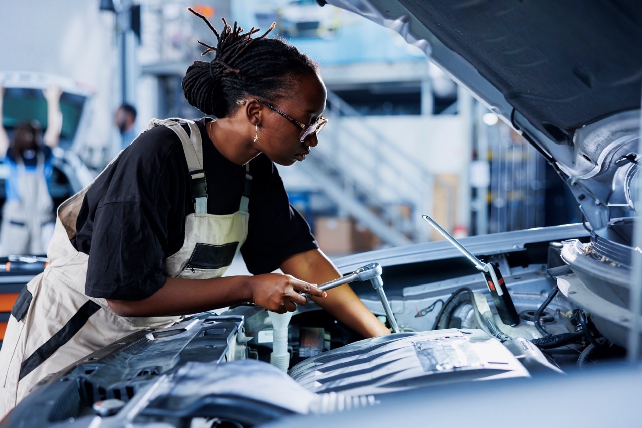 Automotive mechanic uses manual torque wrench to tighten fasteners on a car’s engine block.